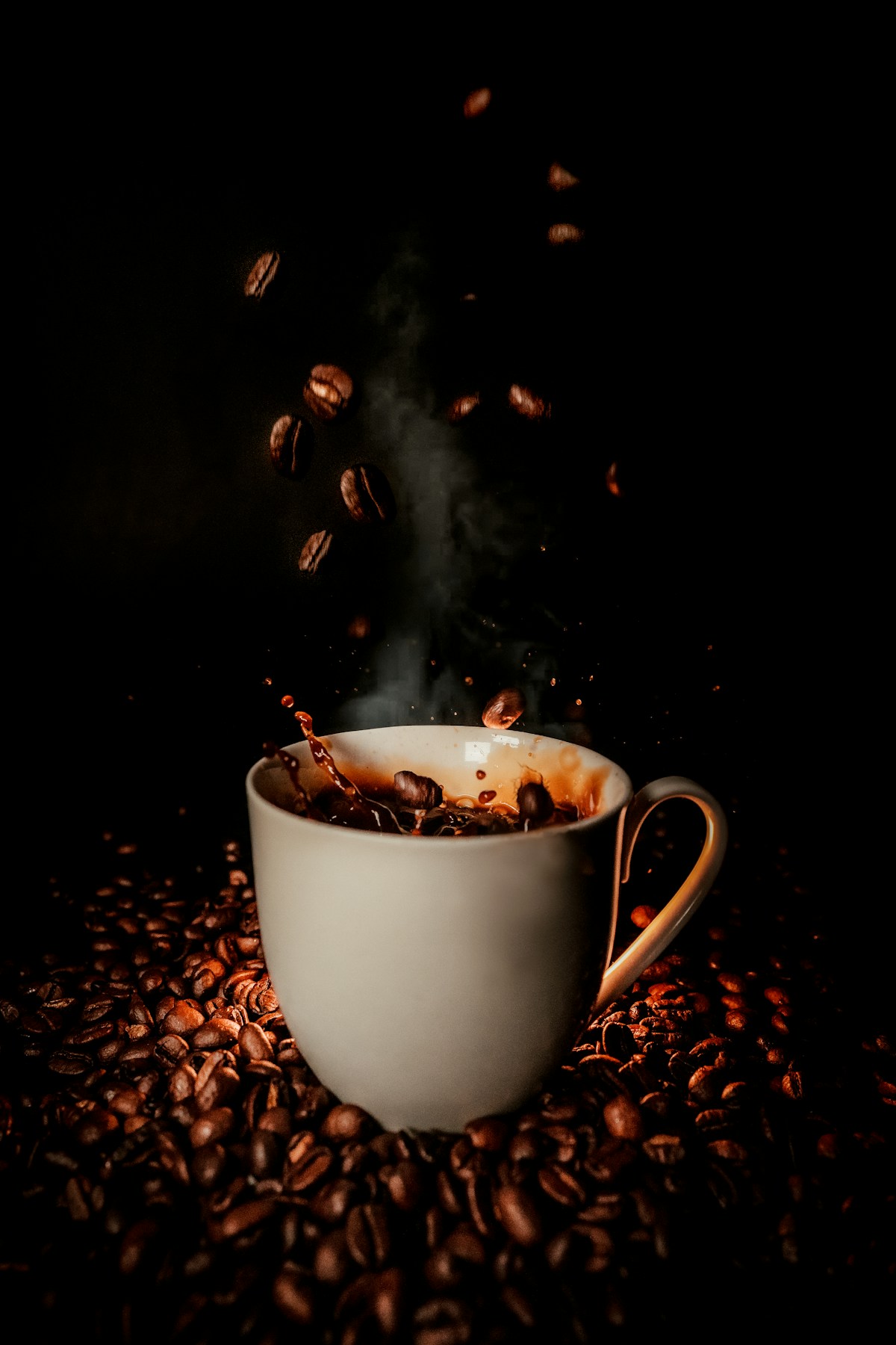 Coffee splashes in a ceramic cup, surrounded by roasted beans